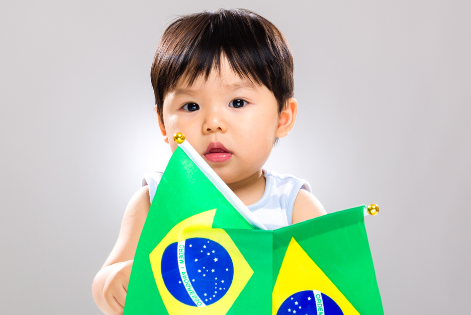 Criança japonesa segurando bandeiras do Brasil, simbolizando conexão entre culturas.